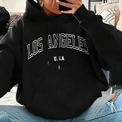 Person wearing a black hoodie with 'Los Angeles U.S.A.' text, sitting on a couch.